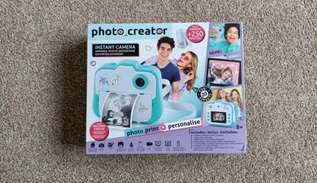 The Photo Creator Instant Camera box, featuring images of the blue and white camera and various smiling people in various poses