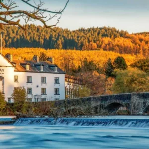 A sunlit hotel behind a stone bridge in the lake district