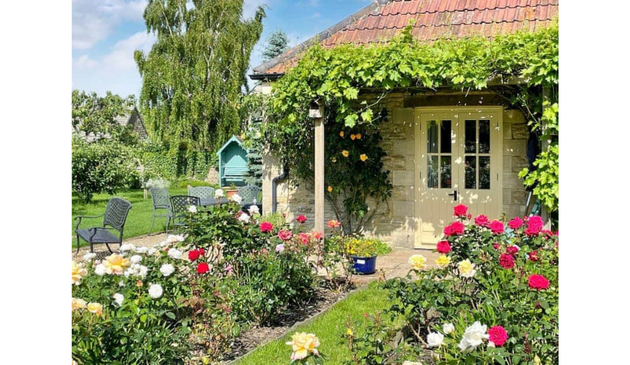 a cottage with lots of flowers in the front garden