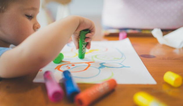 a child drawing with crayons