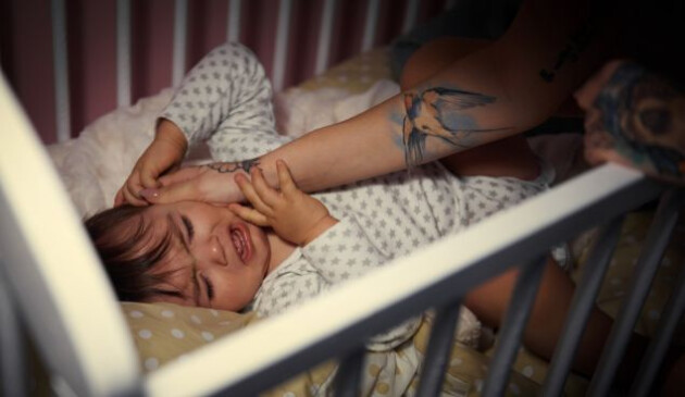 a toddler awake and distressed at night, while her mother tries to comfort her