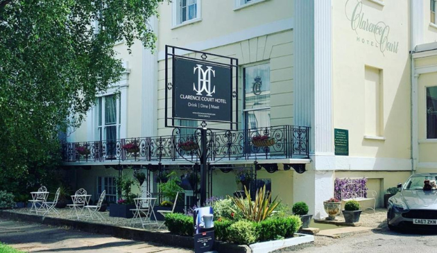 a pale yellow hotel with a black balcony