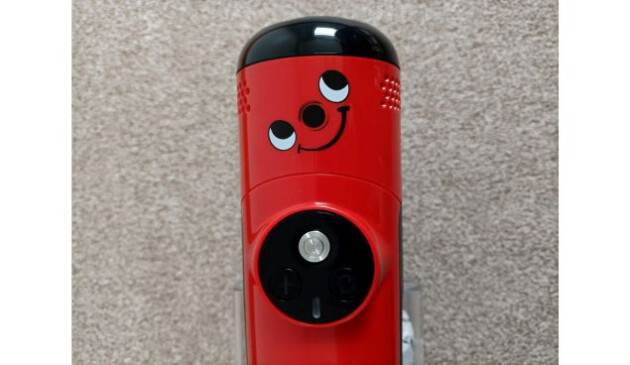A close up of the smiley face on top of the red Henry Quick vacuum cleaner