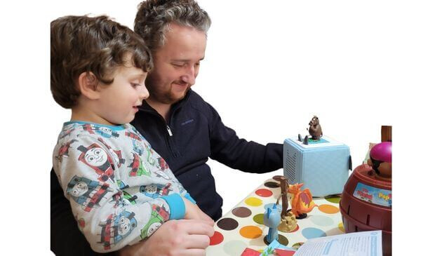 a boy and his dad play with a toniebox