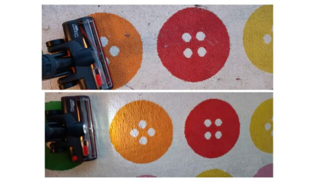 The brush head of a Henry Quick vacuum cleaner being used to hoover pet hair off a rug with a colourful button design