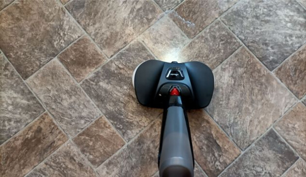 The floorhead of the Vileda Looper spraying water on to brown vinyl kitchen flooring