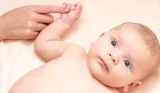 Eight week old baby lying down and holding an adult's finger