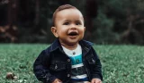 Baby boy smiling while sitting on grass
