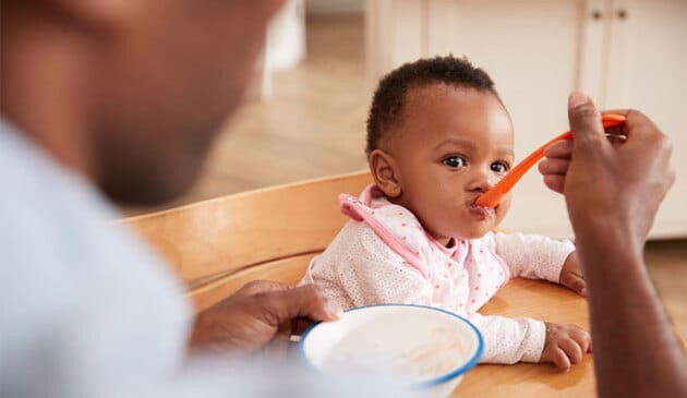 Dad feeding baby in highchair