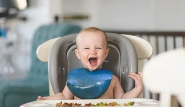 baby in highchair with solid food