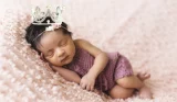 Newborn baby sleeping and wearing small crown