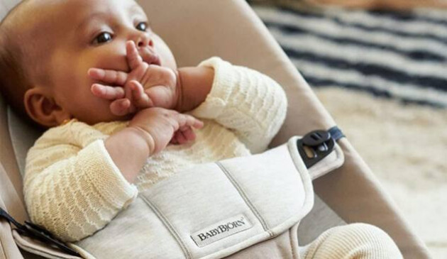 Baby sat in BabyBjorn Bouncer Balance Soft with hand over mouth
