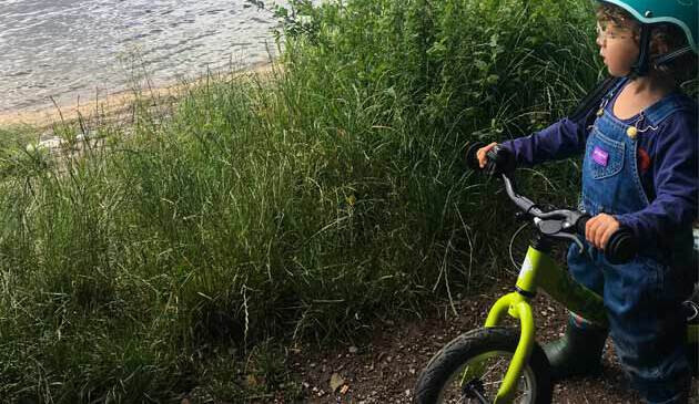 child on balance bike looking out at lake
