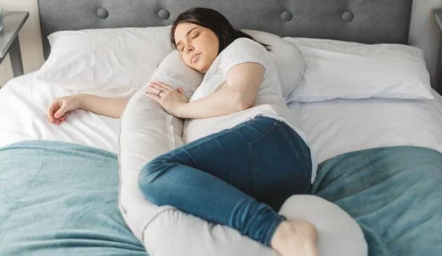 Woman lying on bed using bellamoon pillow