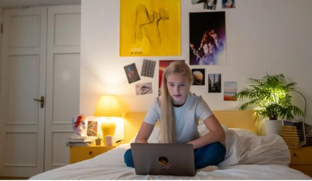 Teenager on laptop in bed