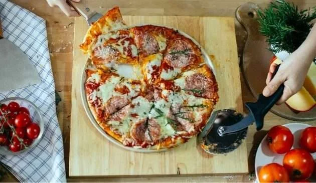 Family using cutter for pizza