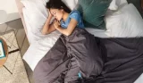 Woman sleeping in bed with blanket