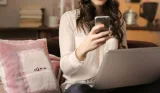 A woman shopping online with a phone and a laptop