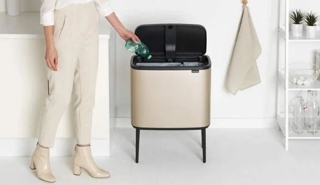 Woman throwing used bottle into kitchen bin