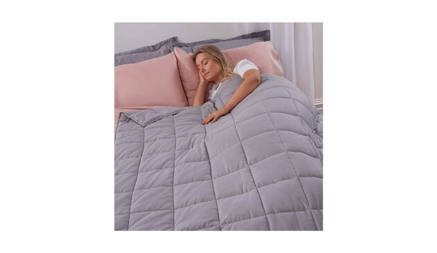 Woman asleep in bed with a grey quilted weighted blanket