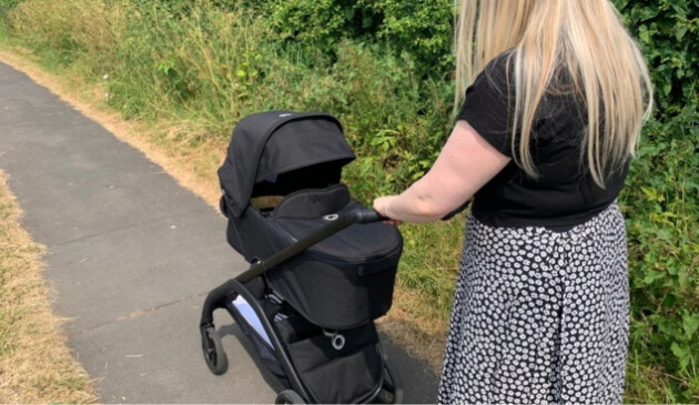 Woman pushing Bugaboo Dragonfly with carrycot on pavement