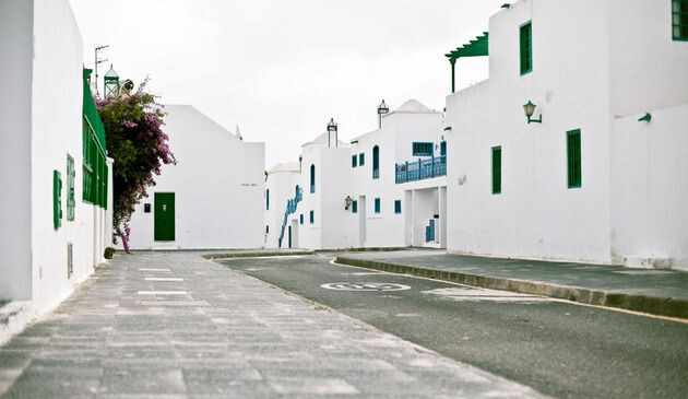White stone buildings with green and blue railings in a tight road