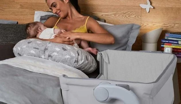 mother holding child next to chicco crib