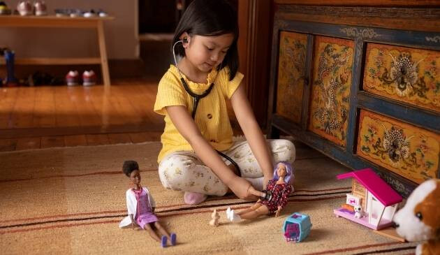 child playing doctors with Barbie dolls
