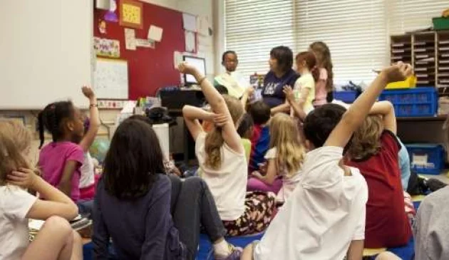 Children in a classroom with hands up