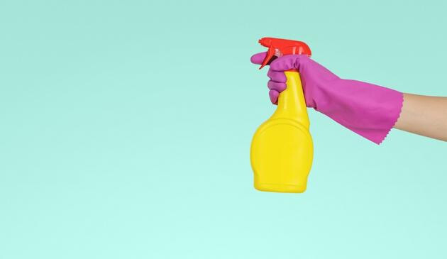 Hand with a rubber glove holding a cleaning spray
