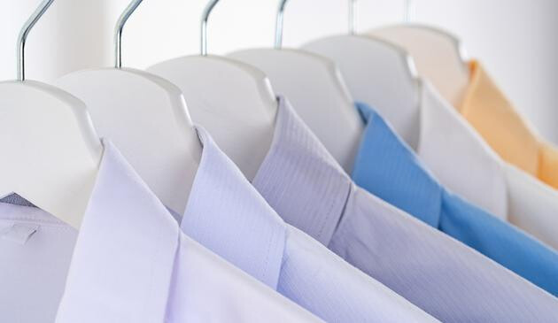 A close up image of work shirts on coat hangers.