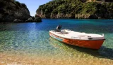 A picture of a boat beached on the sand. Behind it is sea and hills.