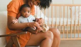 Cute baby boy on mother's lap in nursery