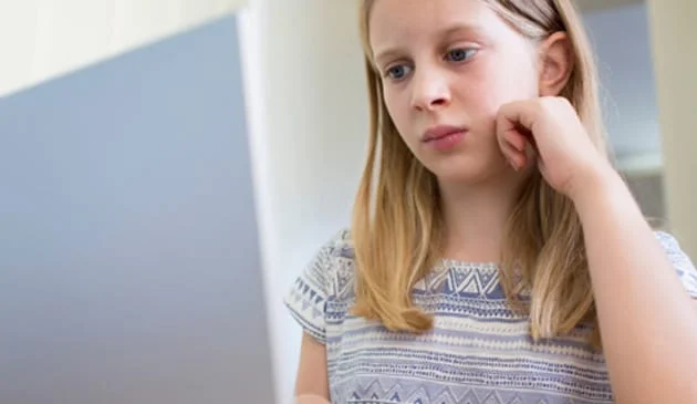 sad girl looks at computer monitor