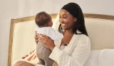 A mother holds her baby in bed
