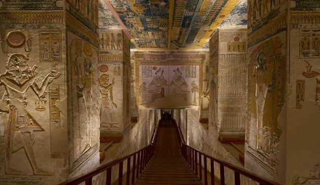 An indoor view of ancient Egyptian pillars with pharonic art on the pillars and a pharoahs head on top of each pillar.
