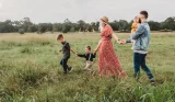 A family of five walking together in the countryside