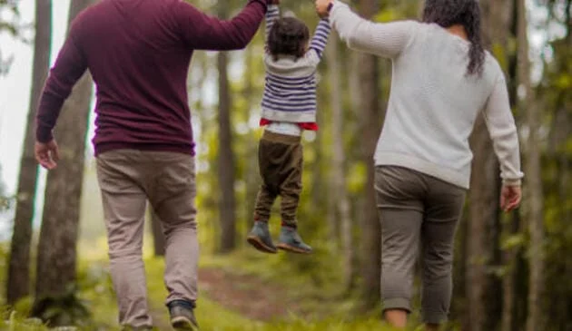 Young child lifted into the air by parents