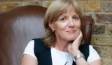 An author photo of Kate Muir sat in a leather arm chair looking at the camera