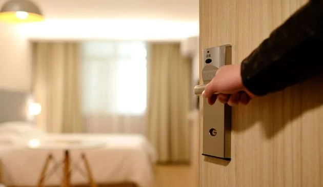 A person opening a door to a hotel room