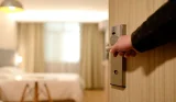 A person opening a door to a hotel room