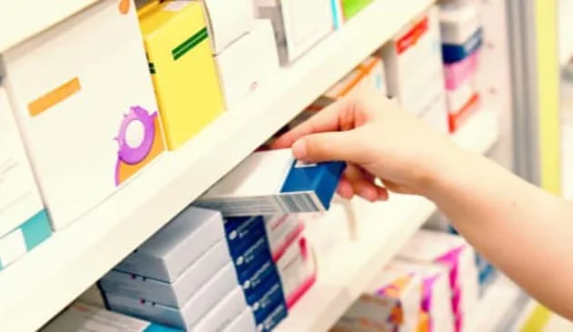 Hand taking medication off pharmacy shelf