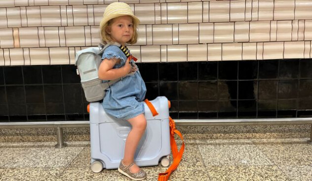 A toddle sits on the JetKids BedBox by Stokke ride on suitcase