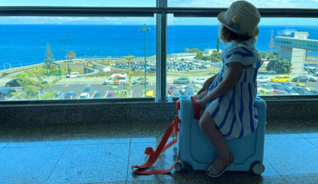A toddler models the JetKids BedBox by Stokke ride on suitcase