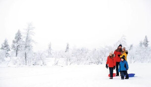 Family posing for a photo in the snow in Lapland