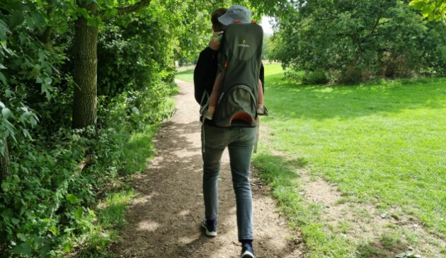 Man walking in country park wearing Littlelife Cross Country S4 carrier with toddler inside