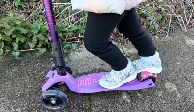 A close up of a child using the brake on the Maxi Micro Scooter