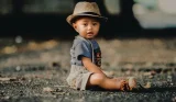 baby. sitting in dungarees and hat