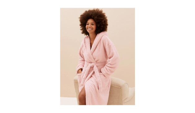 A smiling woman wearing a light pink fleece dressing gown