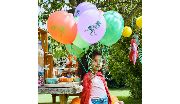 a girl in a red cape holding a bunch of balloons